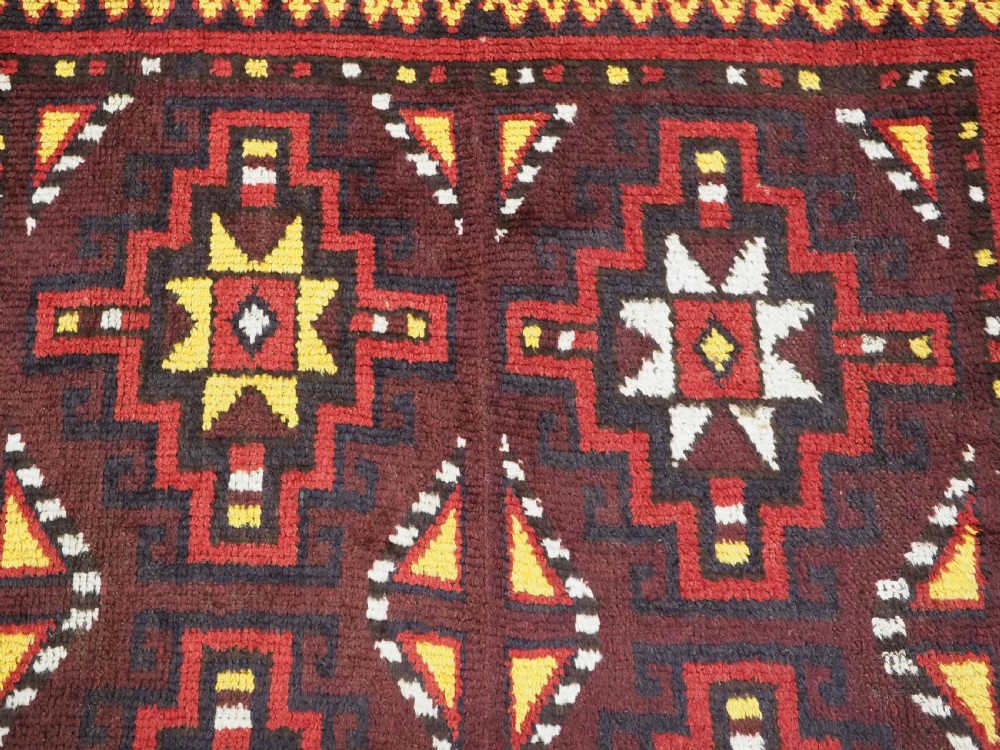 An antique handwoven Uzbek Julkyrs rug with geometric star motifs constructed from four vertical wool strips stitched together in tones of brown, red, and yellow. View XI