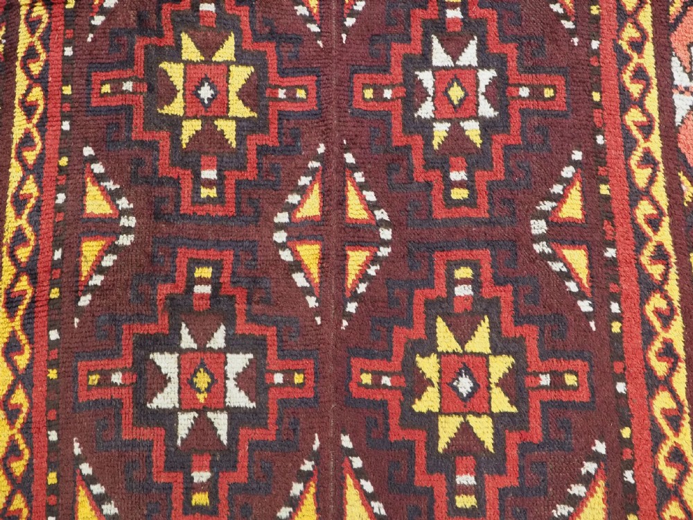 An antique handwoven Uzbek Julkyrs rug with geometric star motifs constructed from four vertical wool strips stitched together in tones of brown, red, and yellow. View XII