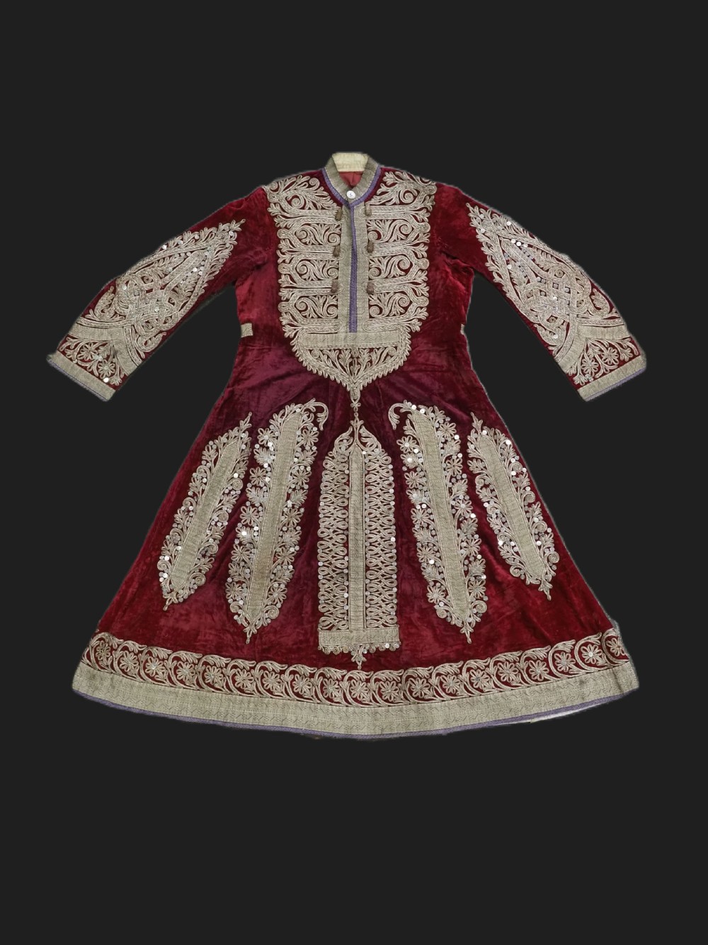 An antique late nineteenth-century Uzbek deep red velvet dress featuring heavy silver metal thread embroidery across the bodice, sleeves, and skirt.