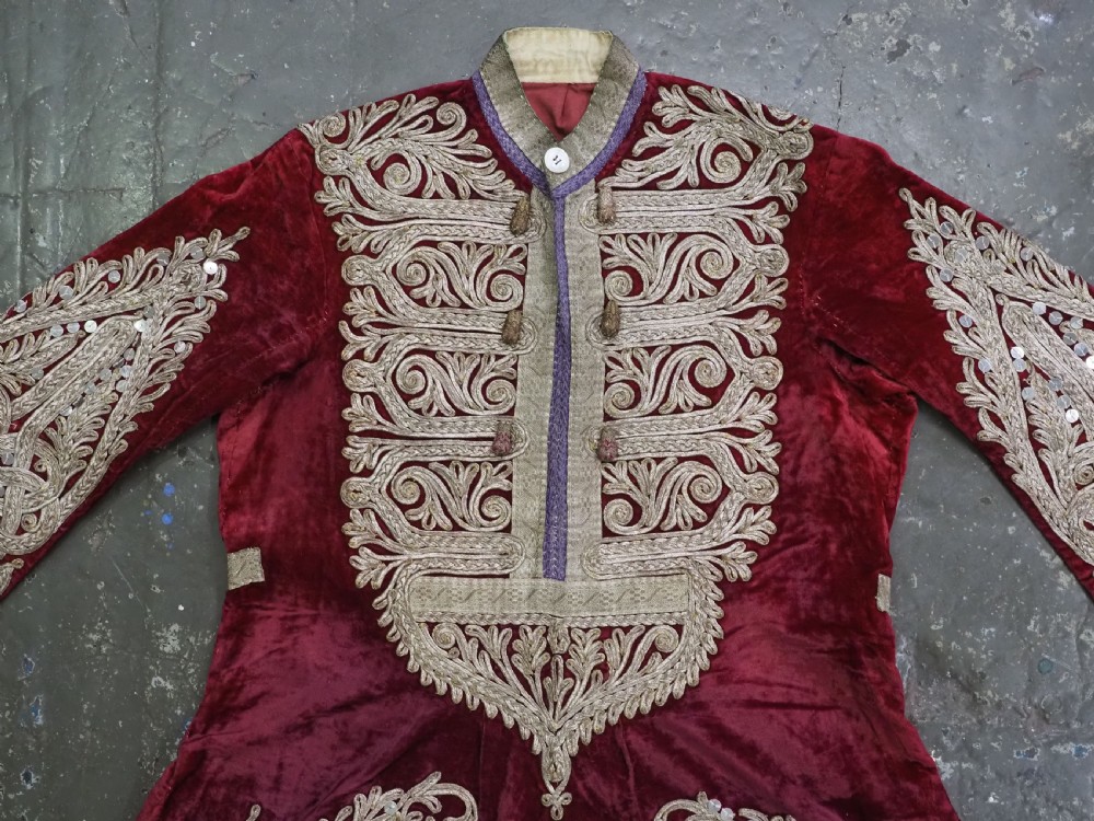 An antique late nineteenth-century Uzbek deep red velvet dress featuring heavy silver metal thread embroidery across the bodice, sleeves, and skirt. View III