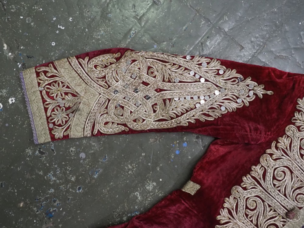 An antique late nineteenth-century Uzbek deep red velvet dress featuring heavy silver metal thread embroidery across the bodice, sleeves, and skirt. View V