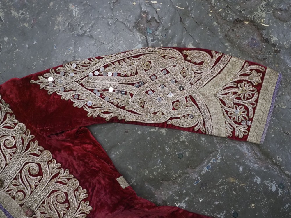 An antique late nineteenth-century Uzbek deep red velvet dress featuring heavy silver metal thread embroidery across the bodice, sleeves, and skirt. View VI
