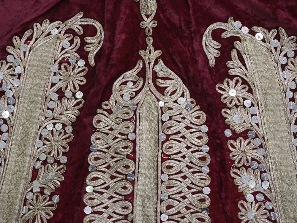 An antique late nineteenth-century Uzbek deep red velvet dress featuring heavy silver metal thread embroidery across the bodice, sleeves, and skirt. View IX