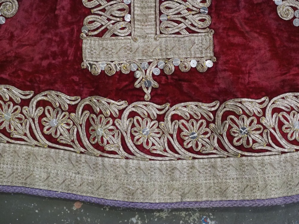 An antique late nineteenth-century Uzbek deep red velvet dress featuring heavy silver metal thread embroidery across the bodice, sleeves, and skirt. View X