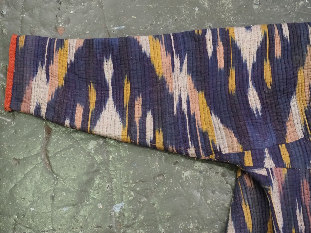 A quilted late 19th-century Uzbek silk ikat chapan coat featuring a bold chevron motif in indigo blue, yellow, and white, framed with red edge trimming. View III