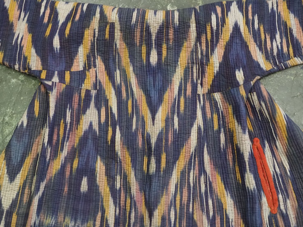 A quilted late 19th-century Uzbek silk ikat chapan coat featuring a bold chevron motif in indigo blue, yellow, and white, framed with red edge trimming. View IV