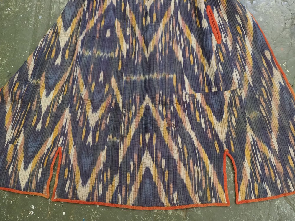 A quilted late 19th-century Uzbek silk ikat chapan coat featuring a bold chevron motif in indigo blue, yellow, and white, framed with red edge trimming. View V