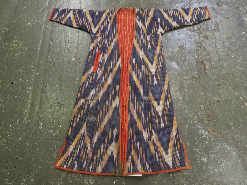 A quilted late 19th-century Uzbek silk ikat chapan coat featuring a bold chevron motif in indigo blue, yellow, and white, framed with red edge trimming. View VIII