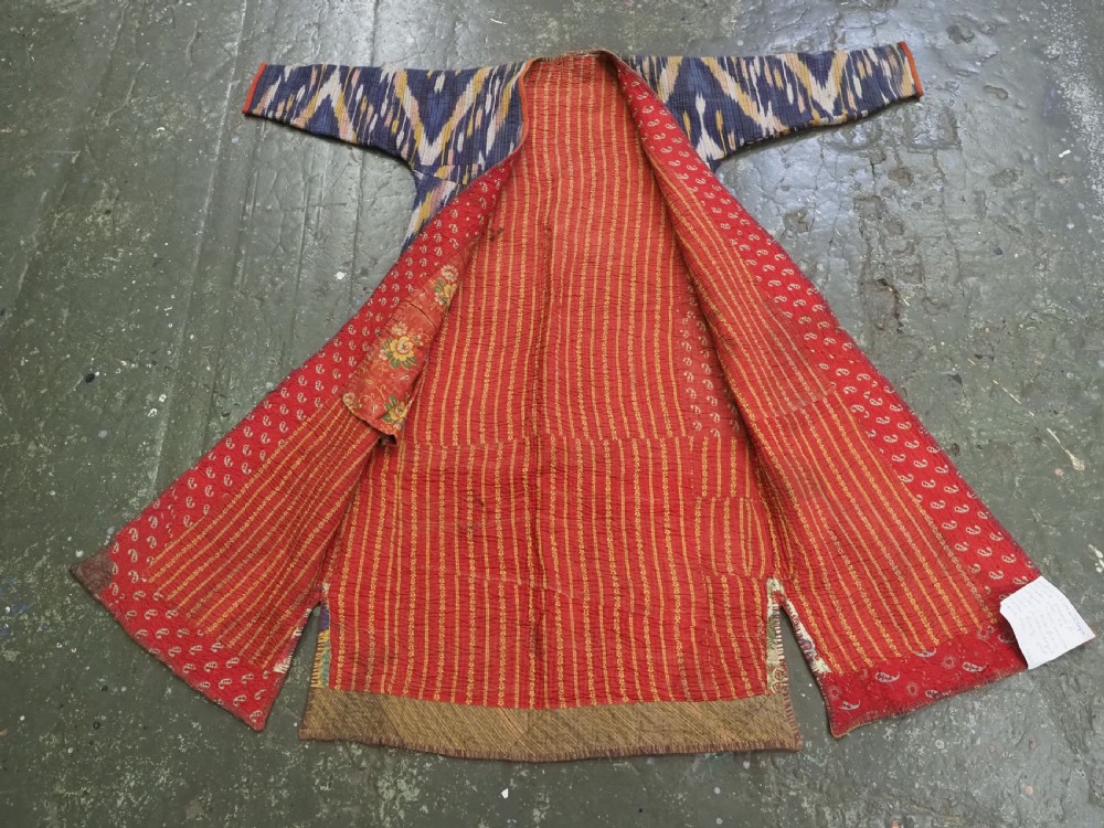 A quilted late 19th-century Uzbek silk ikat chapan coat featuring a bold chevron motif in indigo blue, yellow, and white, framed with red edge trimming. View IX