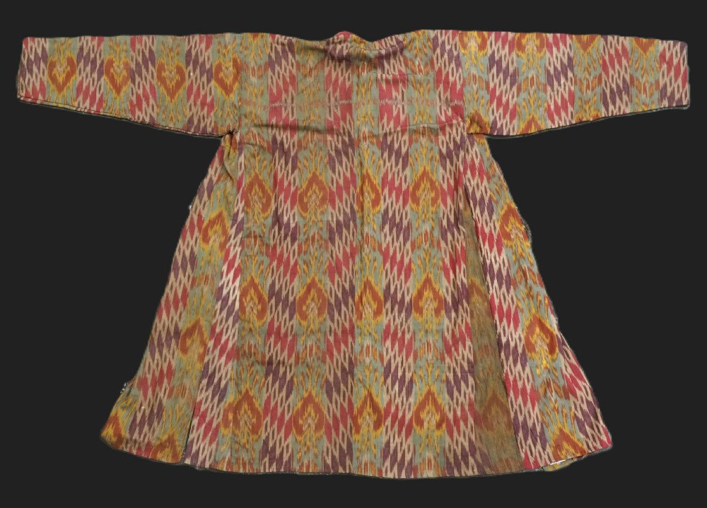 An antique Uzbek silk ikat coat featuring repeating diamond pattern motifs in red, yellow, green, and purple shades with flared sleeves.