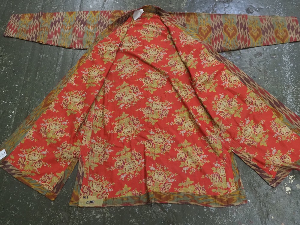 An antique Uzbek silk ikat coat featuring repeating diamond pattern motifs in red, yellow, green, and purple shades with flared sleeves. View XII