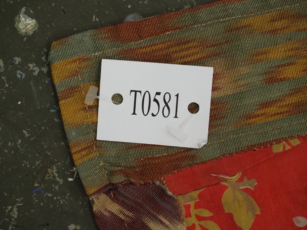 An antique Uzbek silk ikat coat featuring repeating diamond pattern motifs in red, yellow, green, and purple shades with flared sleeves. View XIV