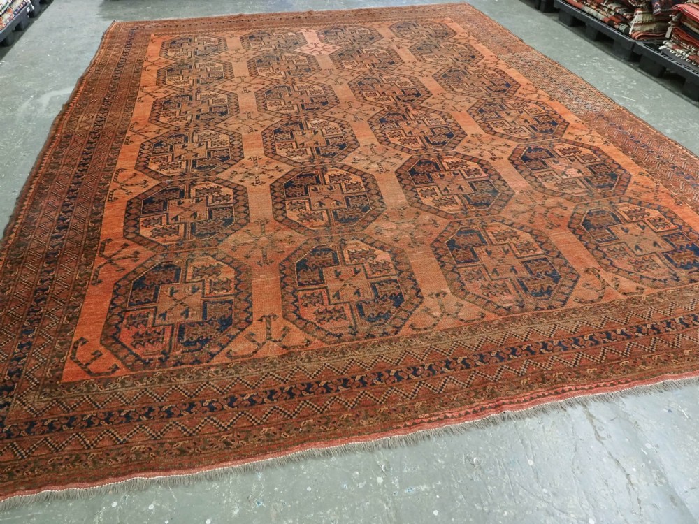 An antique hand-knotted wool carpet featuring repeating octagonal gul motifs on a terracotta background framed by geometric borders. View II