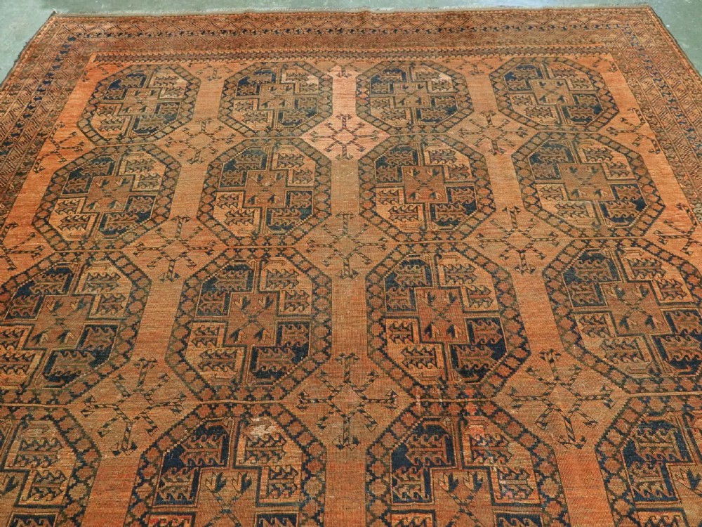 An antique hand-knotted wool carpet featuring repeating octagonal gul motifs on a terracotta background framed by geometric borders. View III