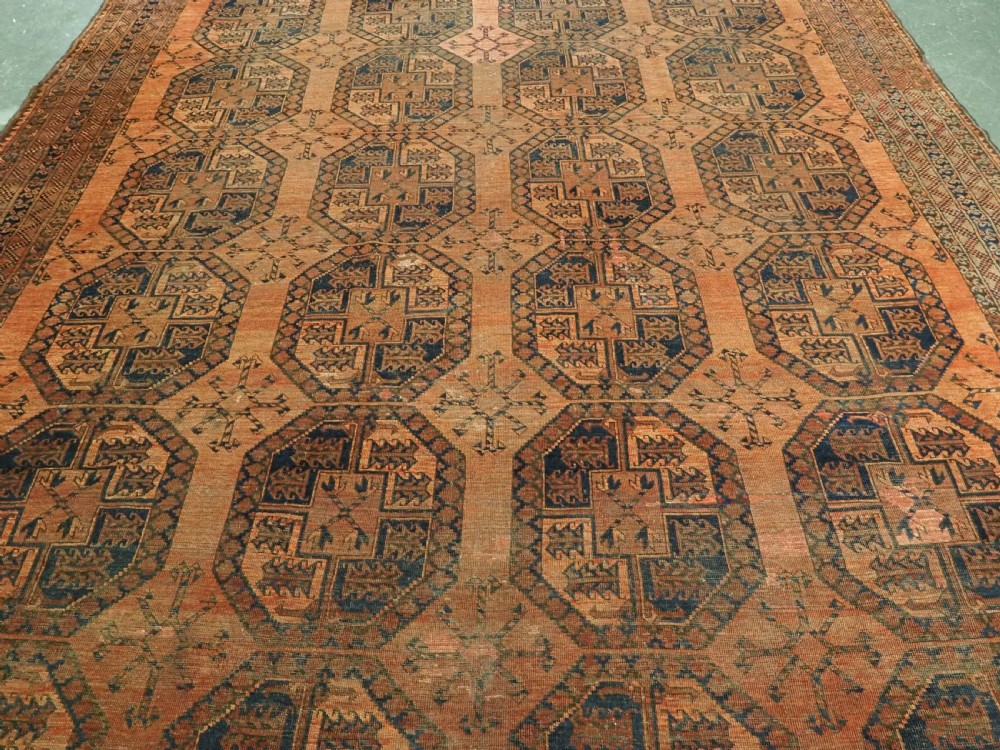 An antique hand-knotted wool carpet featuring repeating octagonal gul motifs on a terracotta background framed by geometric borders. View IV