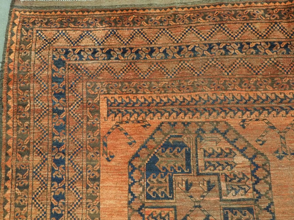 An antique hand-knotted wool carpet featuring repeating octagonal gul motifs on a terracotta background framed by geometric borders. View V