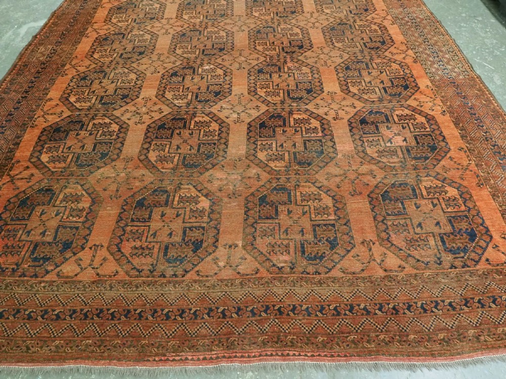 An antique hand-knotted wool carpet featuring repeating octagonal gul motifs on a terracotta background framed by geometric borders. View VI