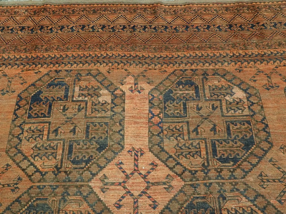 An antique hand-knotted wool carpet featuring repeating octagonal gul motifs on a terracotta background framed by geometric borders. View VIII