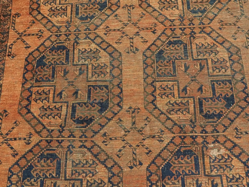 An antique hand-knotted wool carpet featuring repeating octagonal gul motifs on a terracotta background framed by geometric borders. View IX