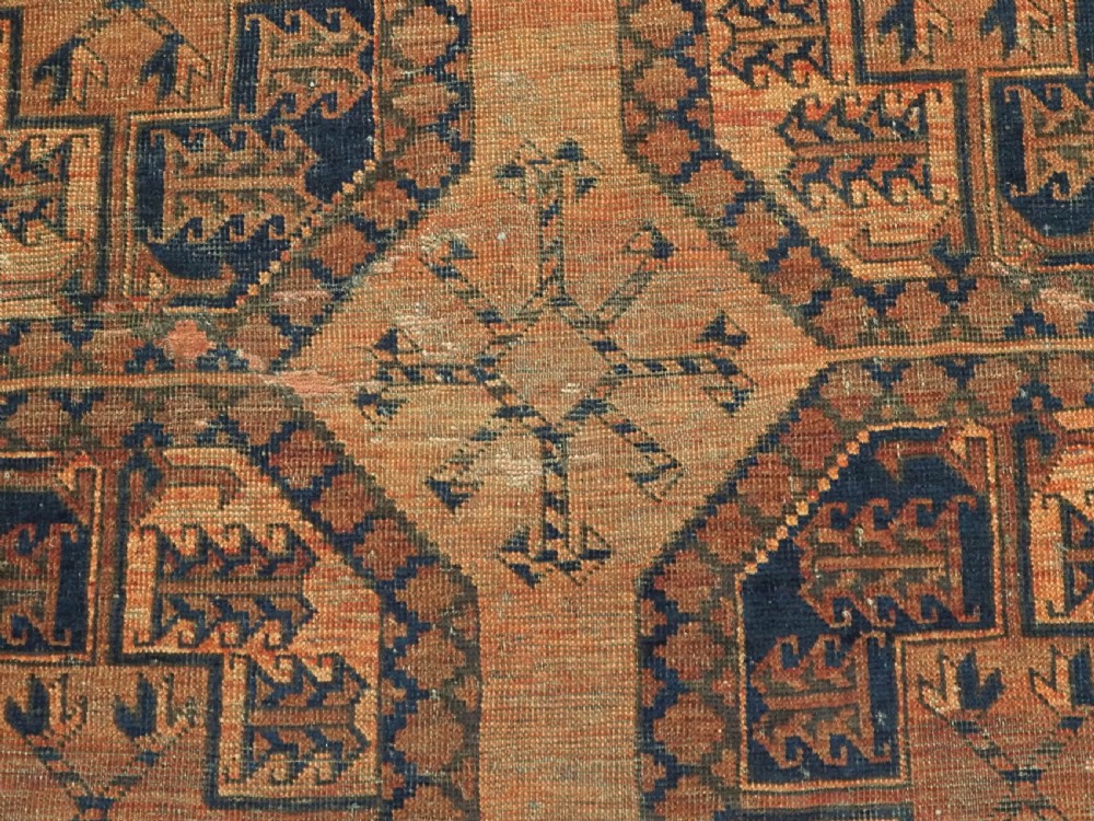 An antique hand-knotted wool carpet featuring repeating octagonal gul motifs on a terracotta background framed by geometric borders. View X