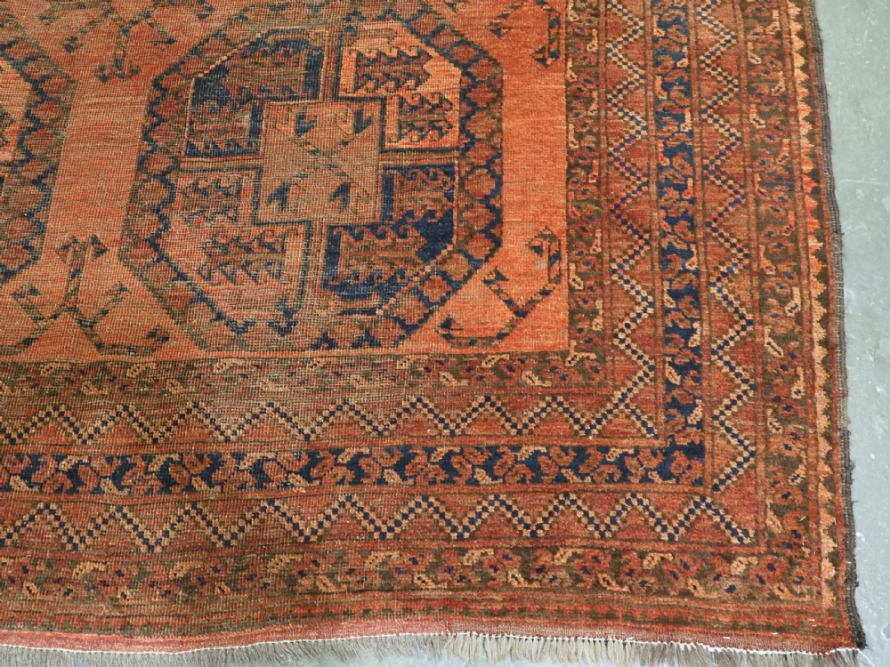 An antique hand-knotted wool carpet featuring repeating octagonal gul motifs on a terracotta background framed by geometric borders. View XII