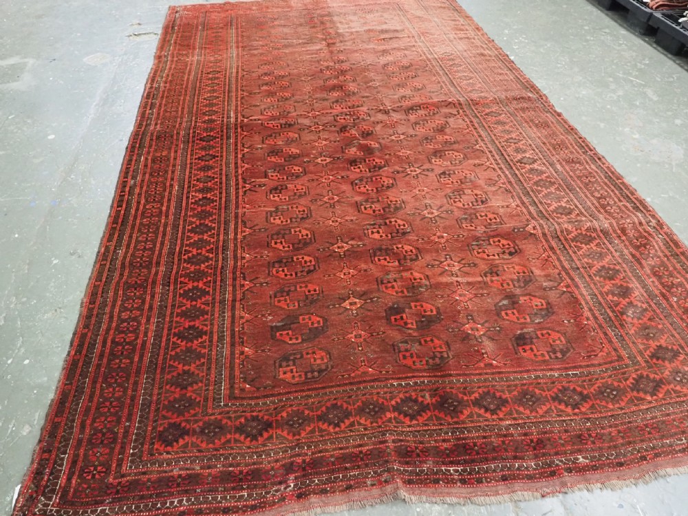 An antique Afghan Kizil Ayak Turkmen wool carpet featuring repeating octagonal gul motifs on a deep red field framed by geometric patterned borders. View II