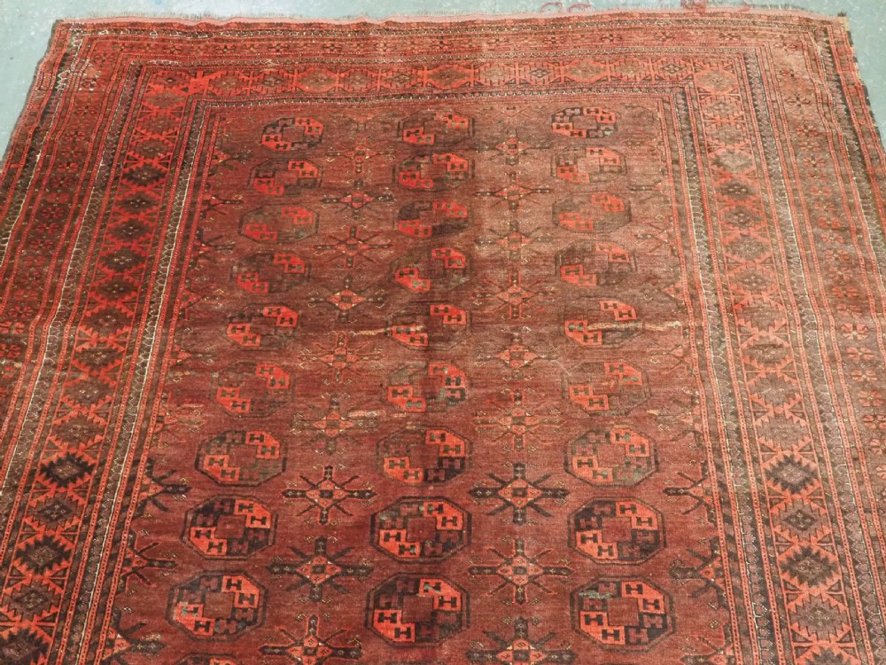 An antique Afghan Kizil Ayak Turkmen wool carpet featuring repeating octagonal gul motifs on a deep red field framed by geometric patterned borders. View III