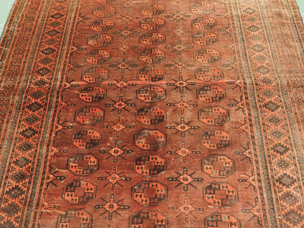 An antique Afghan Kizil Ayak Turkmen wool carpet featuring repeating octagonal gul motifs on a deep red field framed by geometric patterned borders. View IV