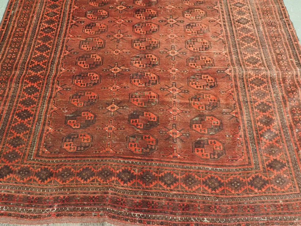 An antique Afghan Kizil Ayak Turkmen wool carpet featuring repeating octagonal gul motifs on a deep red field framed by geometric patterned borders. View V