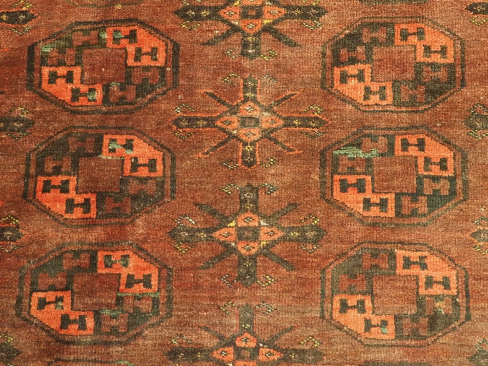 An antique Afghan Kizil Ayak Turkmen wool carpet featuring repeating octagonal gul motifs on a deep red field framed by geometric patterned borders. View IX