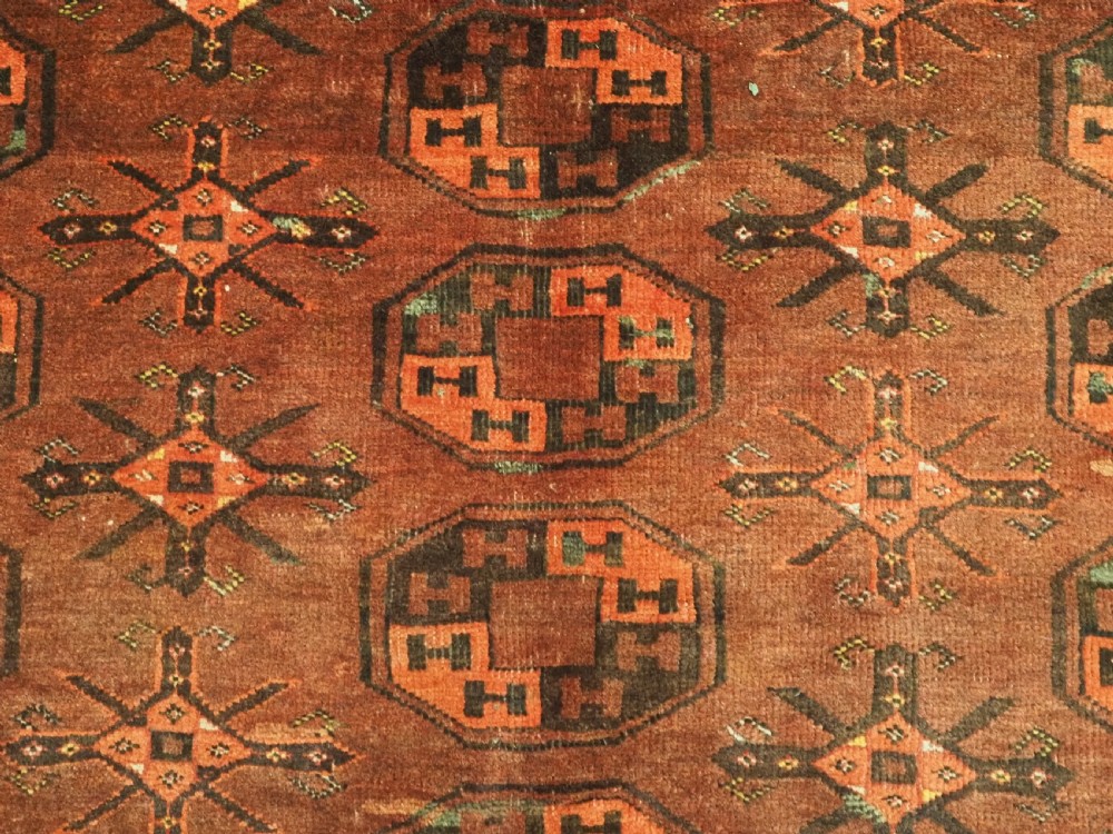 An antique Afghan Kizil Ayak Turkmen wool carpet featuring repeating octagonal gul motifs on a deep red field framed by geometric patterned borders. View X
