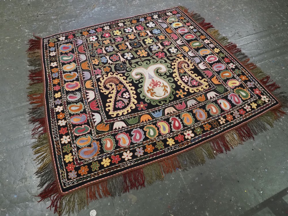 A square black textile decorated with dense multicoloured silk embroidery displaying floral and paisley motifs with fringed edges. View II