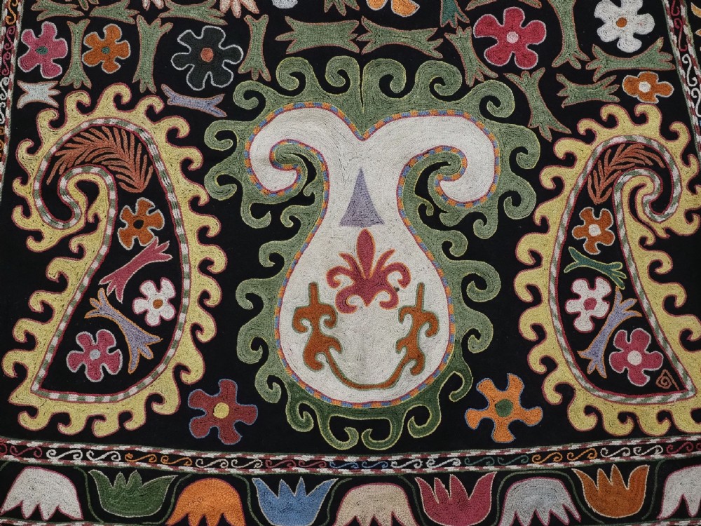 A square black textile decorated with dense multicoloured silk embroidery displaying floral and paisley motifs with fringed edges. View VIII