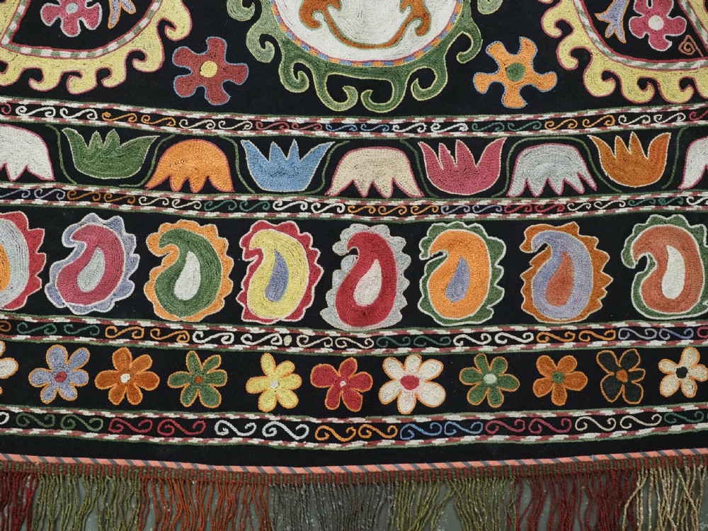A square black textile decorated with dense multicoloured silk embroidery displaying floral and paisley motifs with fringed edges. View XII