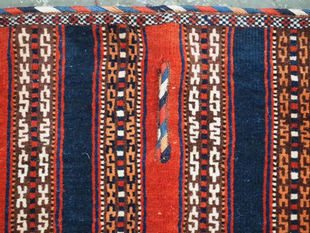 An antique square Turkmen Yomut saddle rug featuring vertical red and navy blue stripes with geometric tribal patterns and woven borders. View VI