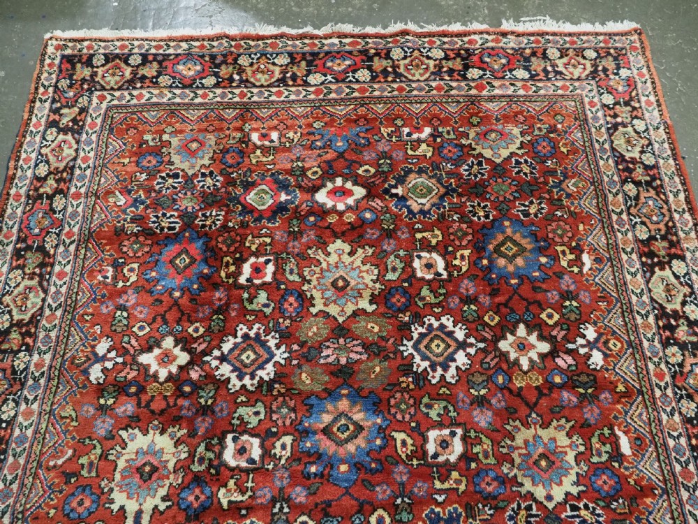 An antique Persian Mahal hand-knotted wool carpet featuring a red central field decorated with an all-over palmette motif and multi-tiered patterned borders. View III