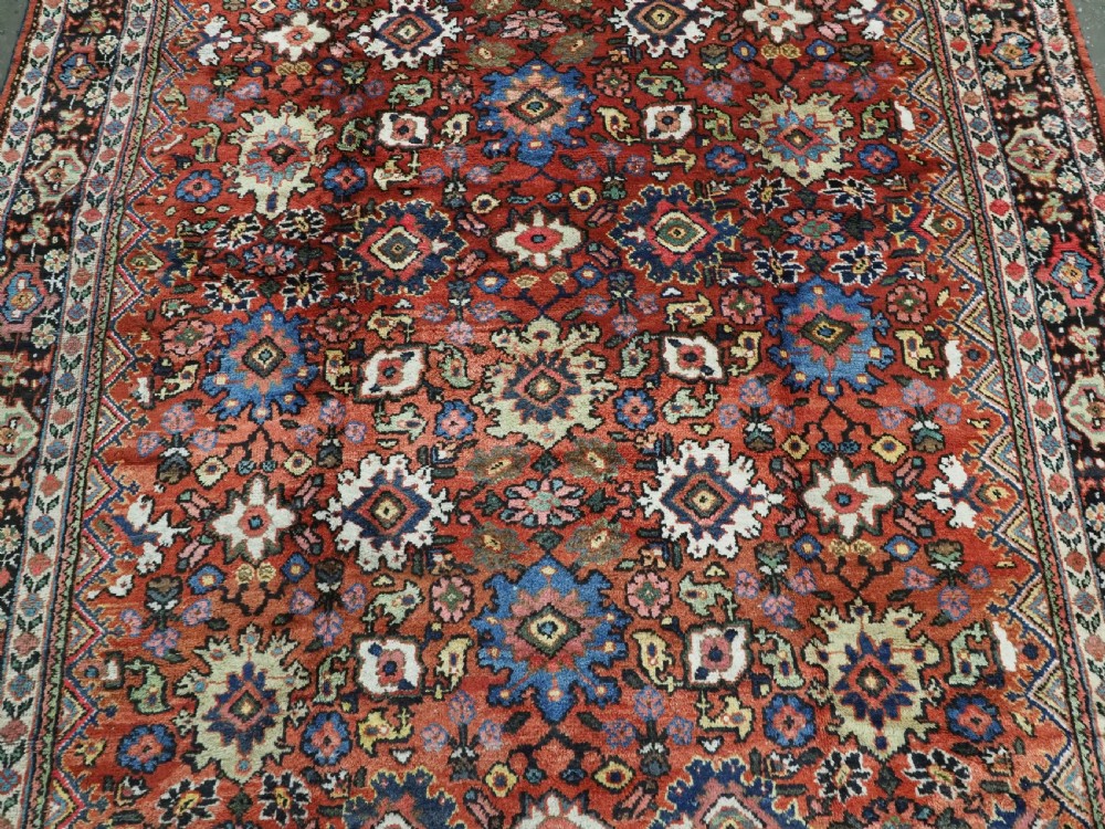 An antique Persian Mahal hand-knotted wool carpet featuring a red central field decorated with an all-over palmette motif and multi-tiered patterned borders. View IV