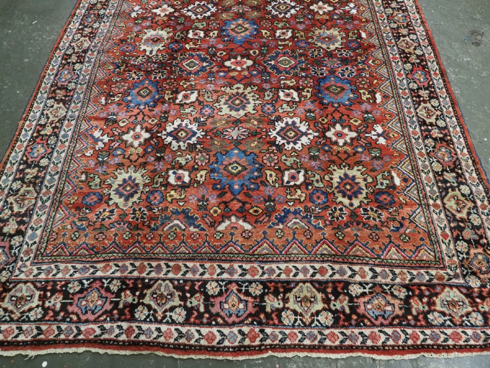 An antique Persian Mahal hand-knotted wool carpet featuring a red central field decorated with an all-over palmette motif and multi-tiered patterned borders. View V