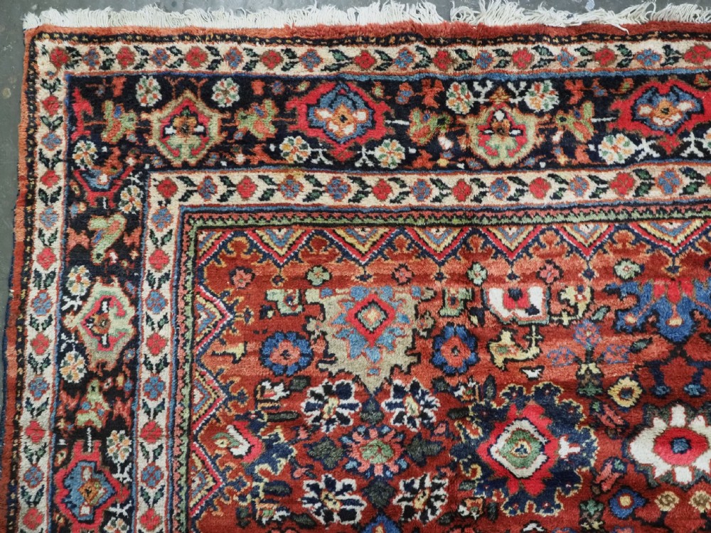 An antique Persian Mahal hand-knotted wool carpet featuring a red central field decorated with an all-over palmette motif and multi-tiered patterned borders. View VI