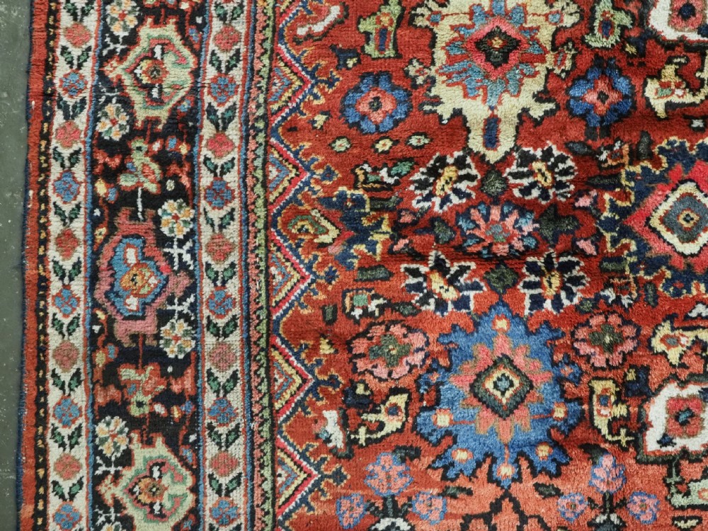 An antique Persian Mahal hand-knotted wool carpet featuring a red central field decorated with an all-over palmette motif and multi-tiered patterned borders. View VII