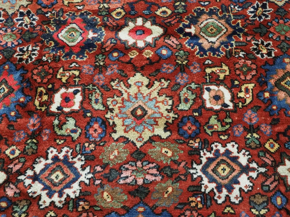An antique Persian Mahal hand-knotted wool carpet featuring a red central field decorated with an all-over palmette motif and multi-tiered patterned borders. View IX