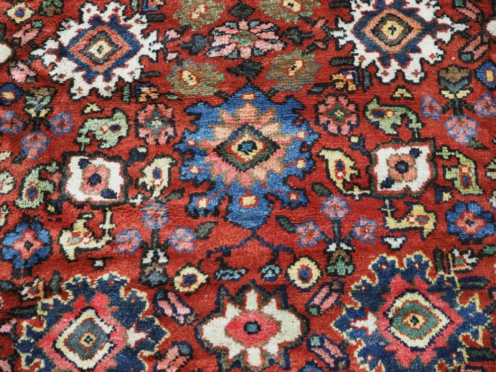 An antique Persian Mahal hand-knotted wool carpet featuring a red central field decorated with an all-over palmette motif and multi-tiered patterned borders. View X