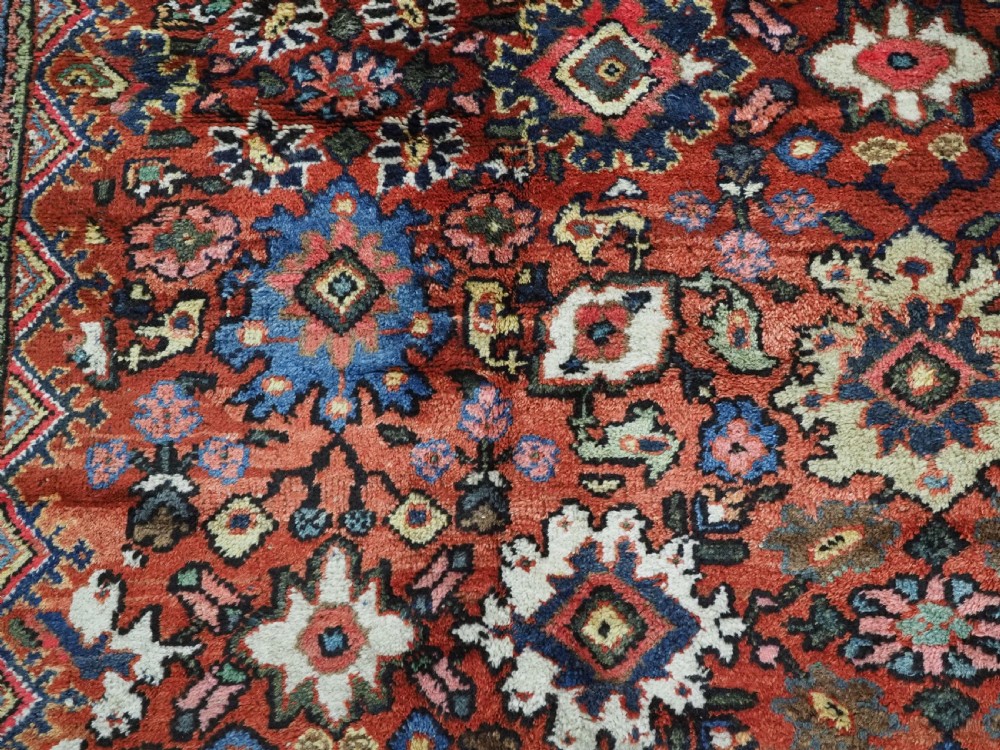 An antique Persian Mahal hand-knotted wool carpet featuring a red central field decorated with an all-over palmette motif and multi-tiered patterned borders. View XI