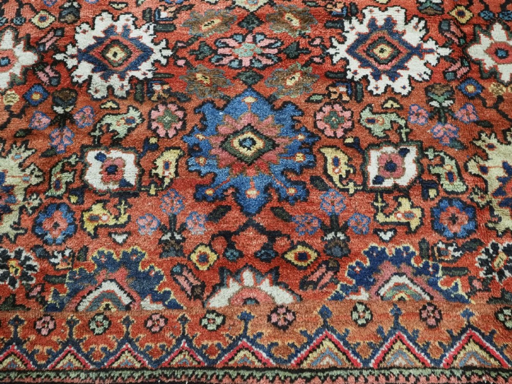 An antique Persian Mahal hand-knotted wool carpet featuring a red central field decorated with an all-over palmette motif and multi-tiered patterned borders. View XII