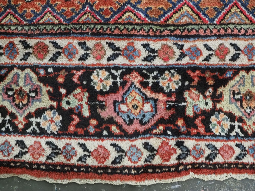 An antique Persian Mahal hand-knotted wool carpet featuring a red central field decorated with an all-over palmette motif and multi-tiered patterned borders. View XVI