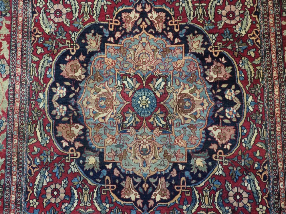An antique hand-knotted Persian Isfahan wool carpet featuring a central starburst medallion surrounded by dense floral vine motifs in red, navy blue, and cream. View XI