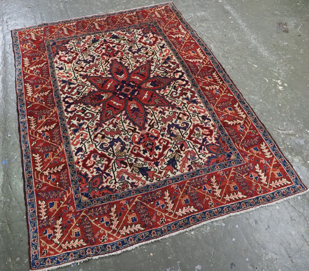 An antique hand-knotted Persian Heriz wool rug featuring a central eight-pointed red star medallion on an ivory ground with a detailed geometric red border. View II