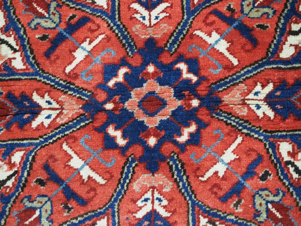 An antique hand-knotted Persian Heriz wool rug featuring a central eight-pointed red star medallion on an ivory ground with a detailed geometric red border. View X