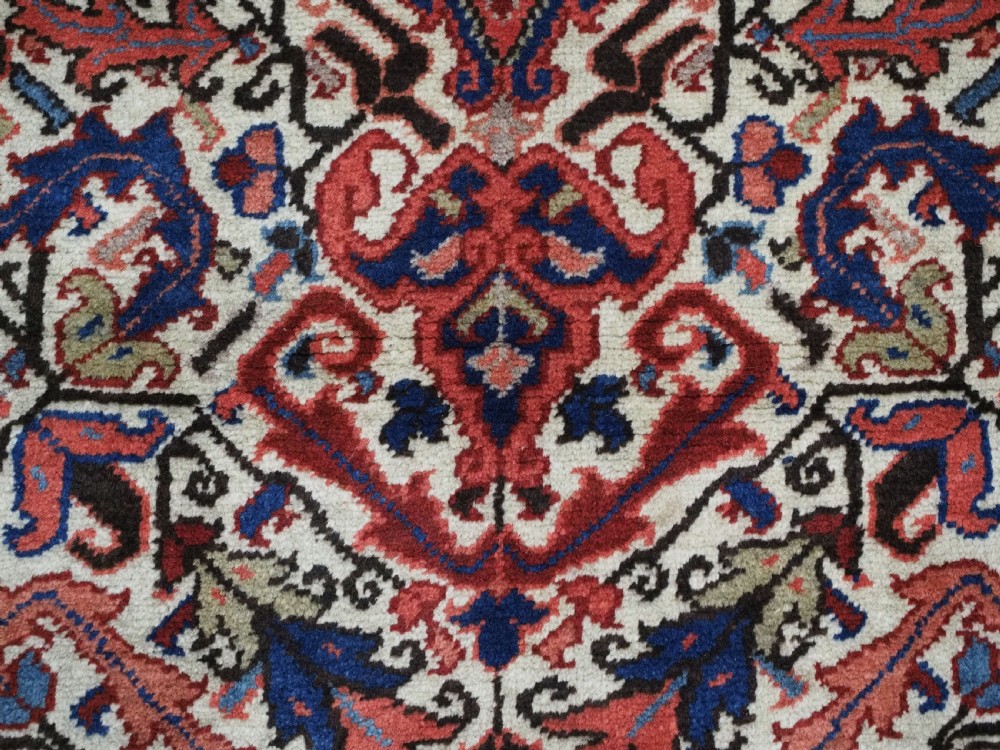 An antique hand-knotted Persian Heriz wool rug featuring a central eight-pointed red star medallion on an ivory ground with a detailed geometric red border. View XI