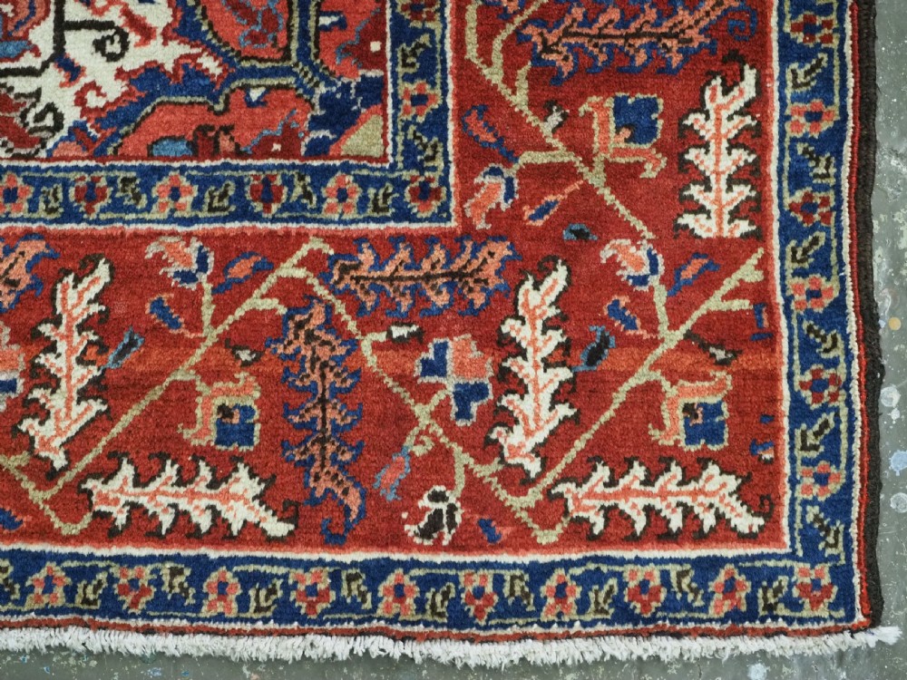 An antique hand-knotted Persian Heriz wool rug featuring a central eight-pointed red star medallion on an ivory ground with a detailed geometric red border. View XIII